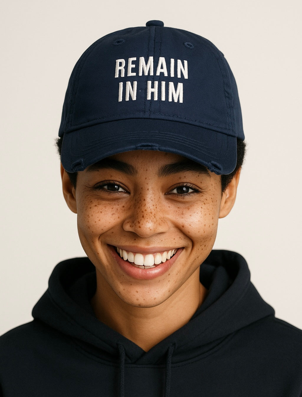 Person wearing a navy blue cap with 'REMAIN IN HIM' text on a plain background