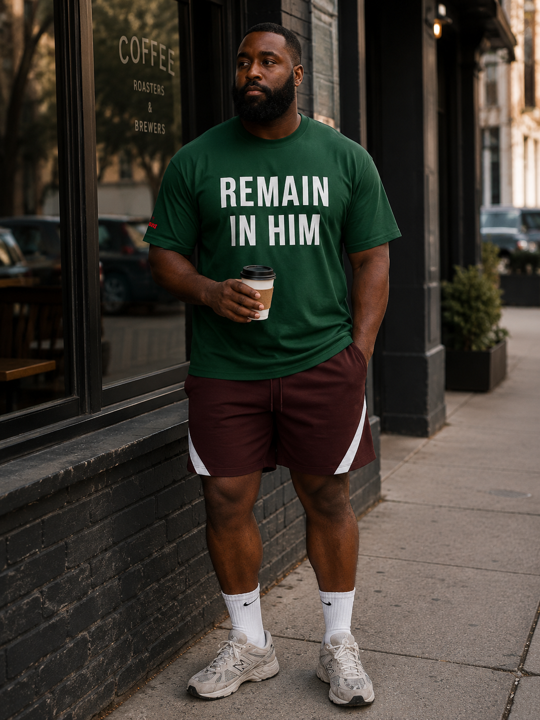 Man wearing a green t-shirt with 'REMAIN IN HIM' text, standing on a sidewalk.