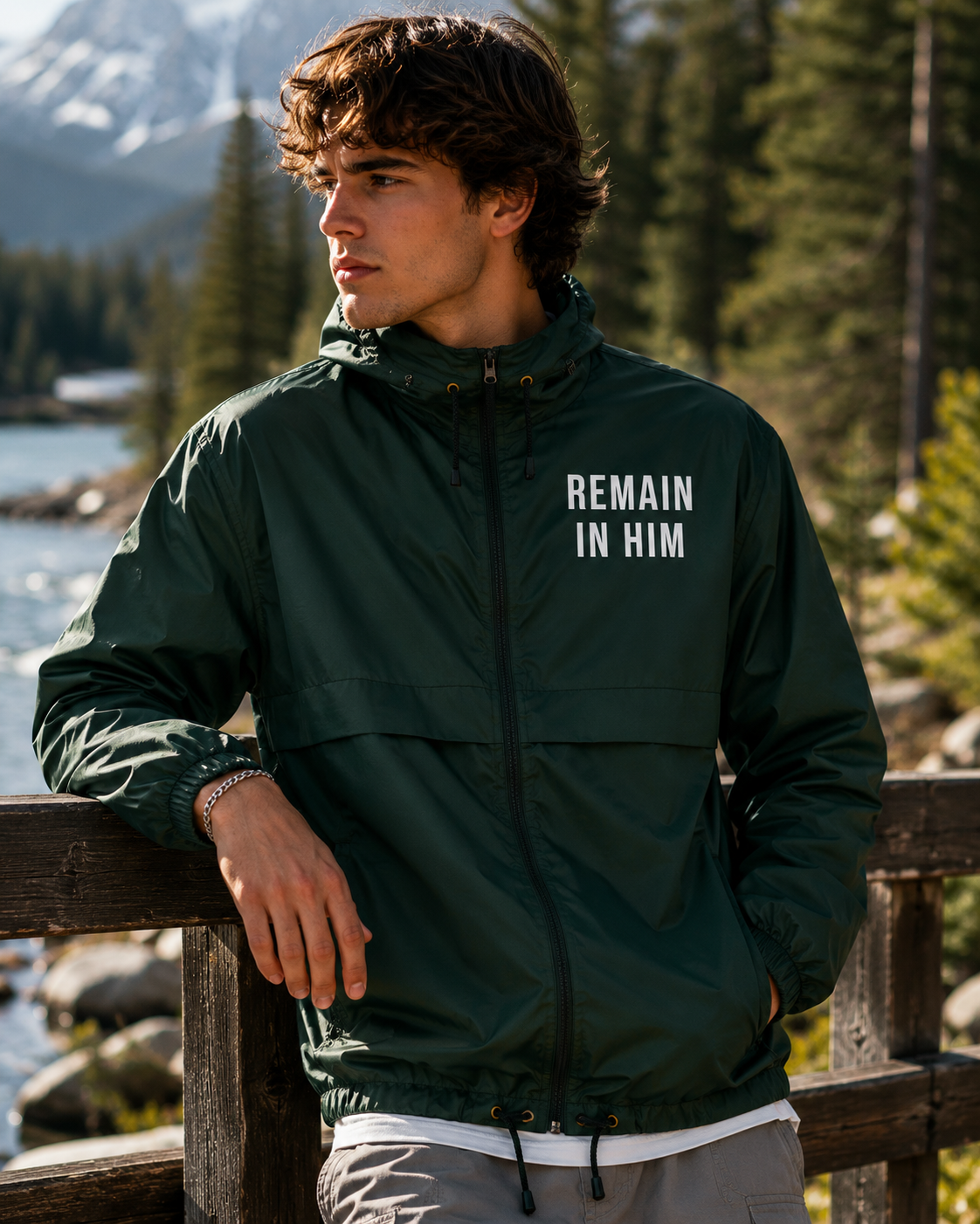 Person wearing a green jacket with 'REMAIN IN HIM' text in a natural setting