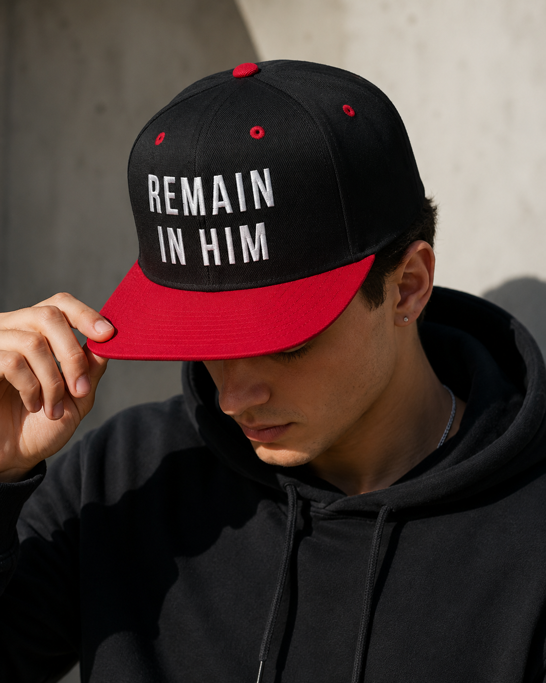 Person wearing a black and red cap with 'REMAIN IN HIM' text against a neutral background